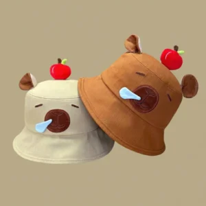 Stack of two cotton bucket hats in brown, and Khaki, each featuring a 3D red apple on top and a sleeping capybara face with a blue bubble on the front.