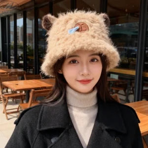 Model wearing a thick, Brown faux-fur bucket hat featuring a sleeping capybara face with a blue 3D snot bubble and brown ears.