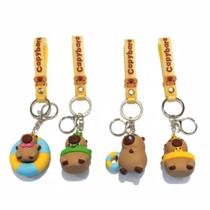 Close-up of a 3D cartoon capybara keychain made of PVC, wearing a green frog swim ring and holding a yellow strap with gold alloy hardware.