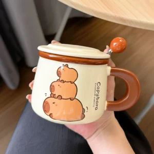 A creamy white ceramic capybara mug featuring three stacked capybaras and "Emotional Stability" text, including a matching lid and an orange-beaded spoon.
