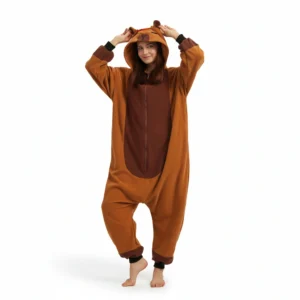 A woman standing on one leg wearing a brown fleece capybara pajama onesie with a hood featuring animal ears, displayed against a white background.