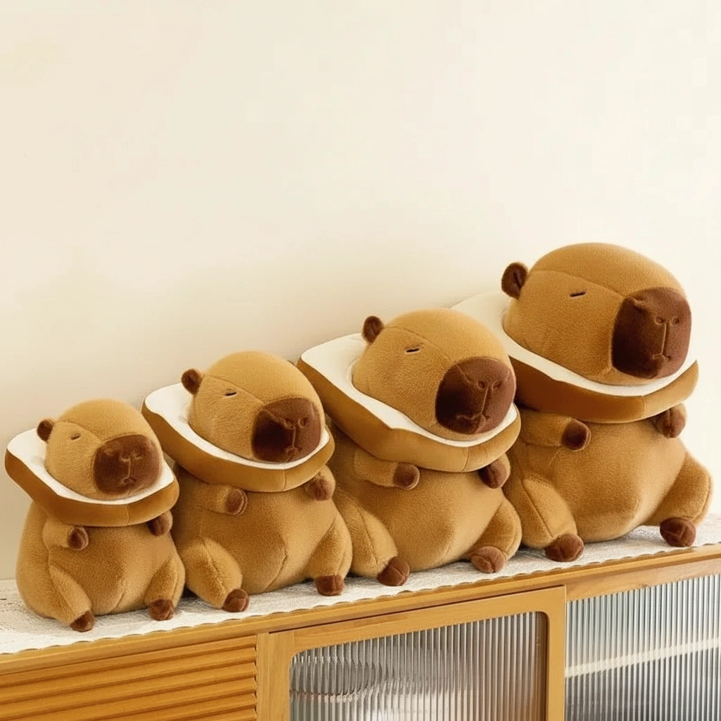 A sitting brown capybara plush toy wearing a removable white and brown plush toast bread collar around its neck.