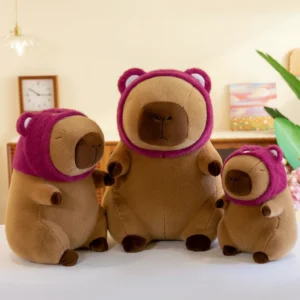 Three brown capybara plush toys sitting in a row, wearing magenta strawberry bear hoods with white ears, ranging in size from small to large.