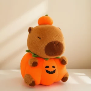 Adorable Halloween capybara plush toy sitting inside a round orange pumpkin costume with a Jack-o'-lantern face and a small pumpkin hat on its head.
