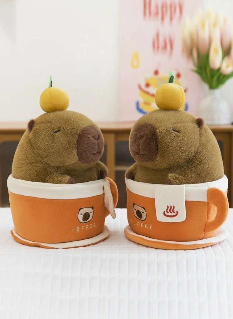 brown capybara plush with an orange on its head sitting inside a removable orange coffee cup plush toy