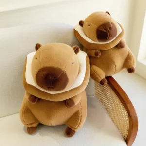 A sitting brown capybara plush toy wearing a removable white and brown plush toast bread collar around its neck.