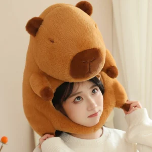 A young woman wearing a large, fluffy brown capybara plush hat that covers the head and ears, featuring a cute sleeping capybara face.