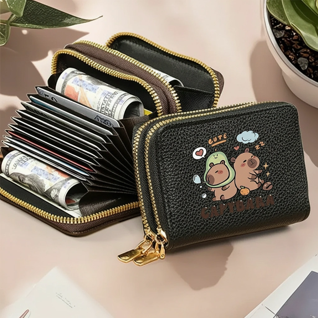 Double-zipper accordion wallet featuring a cartoon capybara in an avocado costume, shown with zippers open to reveal multiple card slots and cash storage.