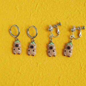 Adorable 3D capybara earrings featuring a tiny turtle on the capybara's head, shown in both gold hoop and adjustable spiral clip-on styles.