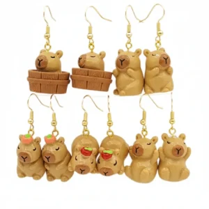 A variety of 3D resin capybara dangle earrings showing designs like a capybara in a wooden bathtub and others with an orange or apple on their heads.