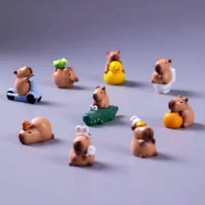 A 12-piece set of miniature capybara figures in various social poses, including one with a bird friend and others with oranges, alongside three small terrain accessories.