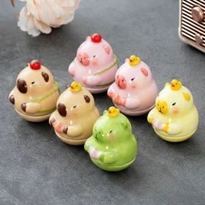 A collection of six colorful ceramic capybara mini figure tumblers in pink, brown, yellow, and green, each featuring a tiny strawberry or duck on its head.