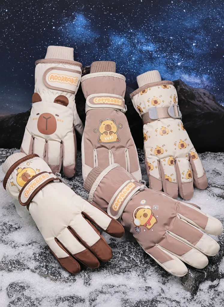 Collection of waterproof winter ski gloves featuring cartoon capybara prints, shown in cream, cocoa, and patterned styles, demonstrating water resistance and thick plush lining.