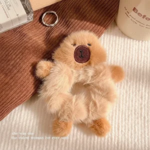 Top-down view of a shaggy beige plush capybara scrunchie featuring small 3D arms and legs, designed to look like it is hugging the wearer's wrist or hair.