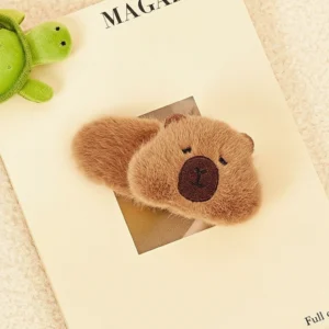 Top-down view of a shaggy, faux fur capybara hair clip with a loaf shape and embroidered face details, showing its fluffy brown texture.