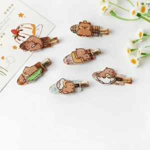 Flat lay of six acrylic capybara hair clips with plaid patterns, featuring designs like a capybara holding a knife, hugging a goose, and riding a crocodile.