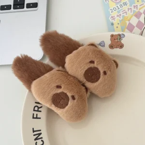Close-up of a fuzzy, brown plush capybara hair clip with embroidered face details and a soft stuffed texture.