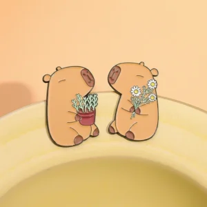 Two cute enamel pins featuring a capybara holding a potted plant and another holding a bunch of white daisy flowers.