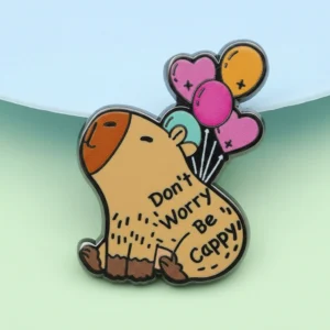 A cartoon enamel pin of a sitting capybara with the text "Don't Worry Be Cappy" on its body, being lifted by a bunch of colorful heart and round balloons.
