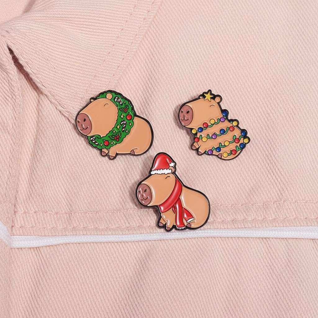 Set of three Christmas-themed enamel pins featuring a capybara in a Santa outfit, one wearing a holiday wreath, and one wrapped in colorful string lights.