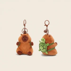 Front view of a capybara plush keychain wearing a green turtle backpack, featuring a brown clasp and bell.
