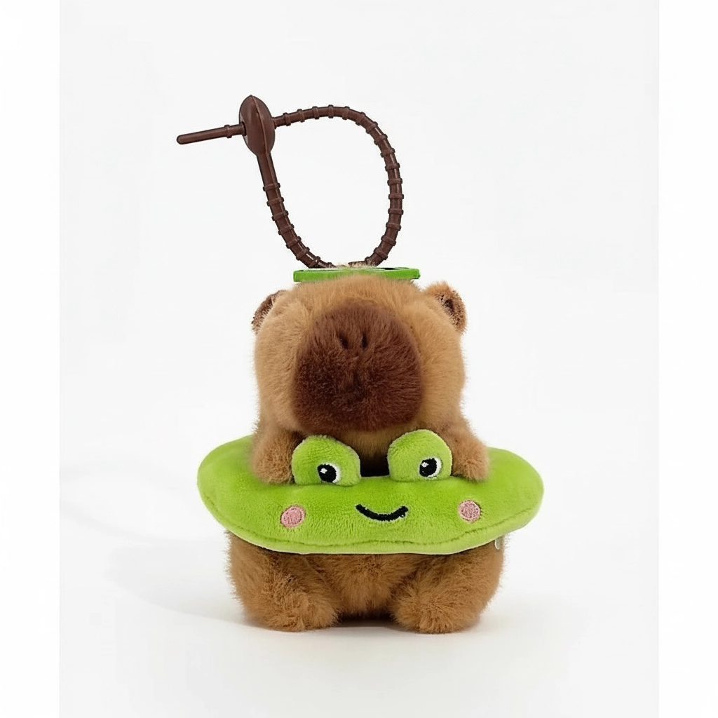 Capybara plushie featuring a green frog swim ring with eyes, hanging from a metal clasp.