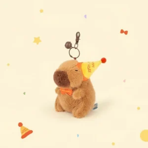Side view of the birthday capybara plush showing the strap of the party hat and the bronze keychain clasp.