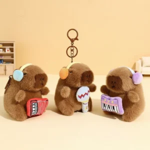 Three capybara plush keychains wearing earmuffs and holding a red accordion, blue microphone, and purple keyboard.